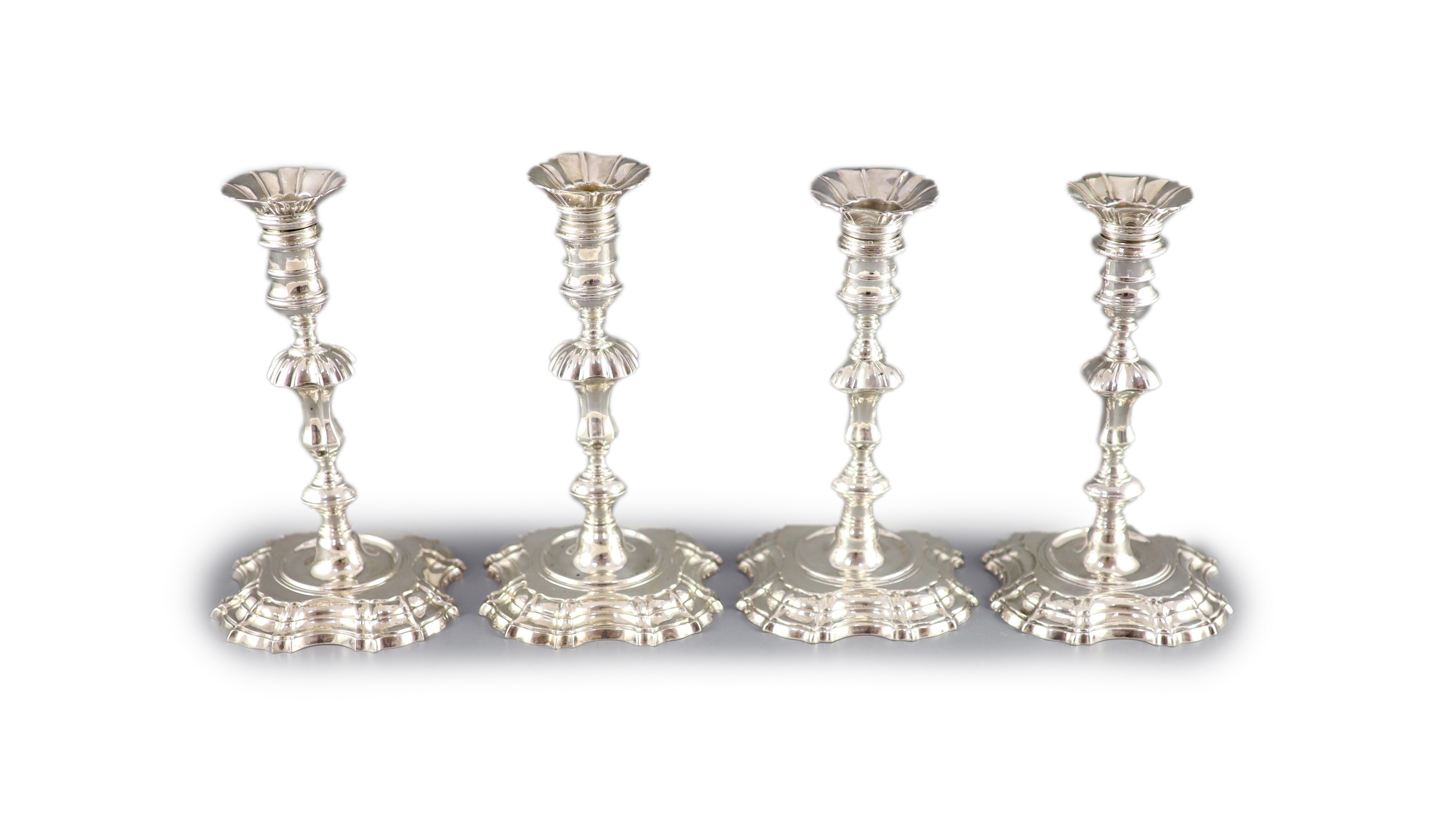 A near set of four George II cast silver candlesticks, by John Cafe